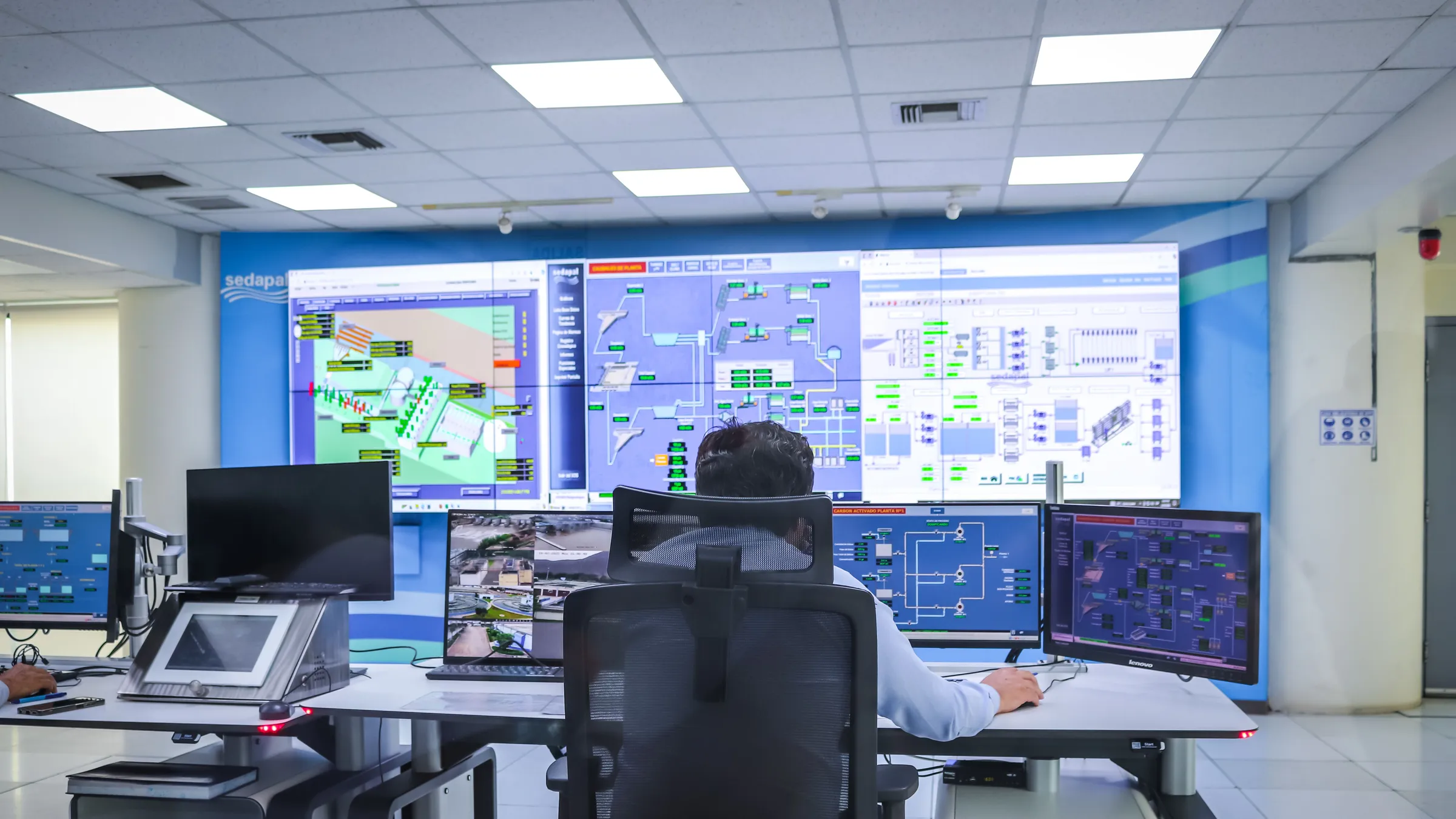 Operator in einem SCADA-Kontrollraum mit großer Monitorwand