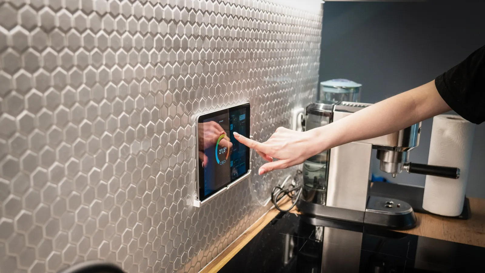 Hand tippt auf ein Wand-Tablet in der Küche