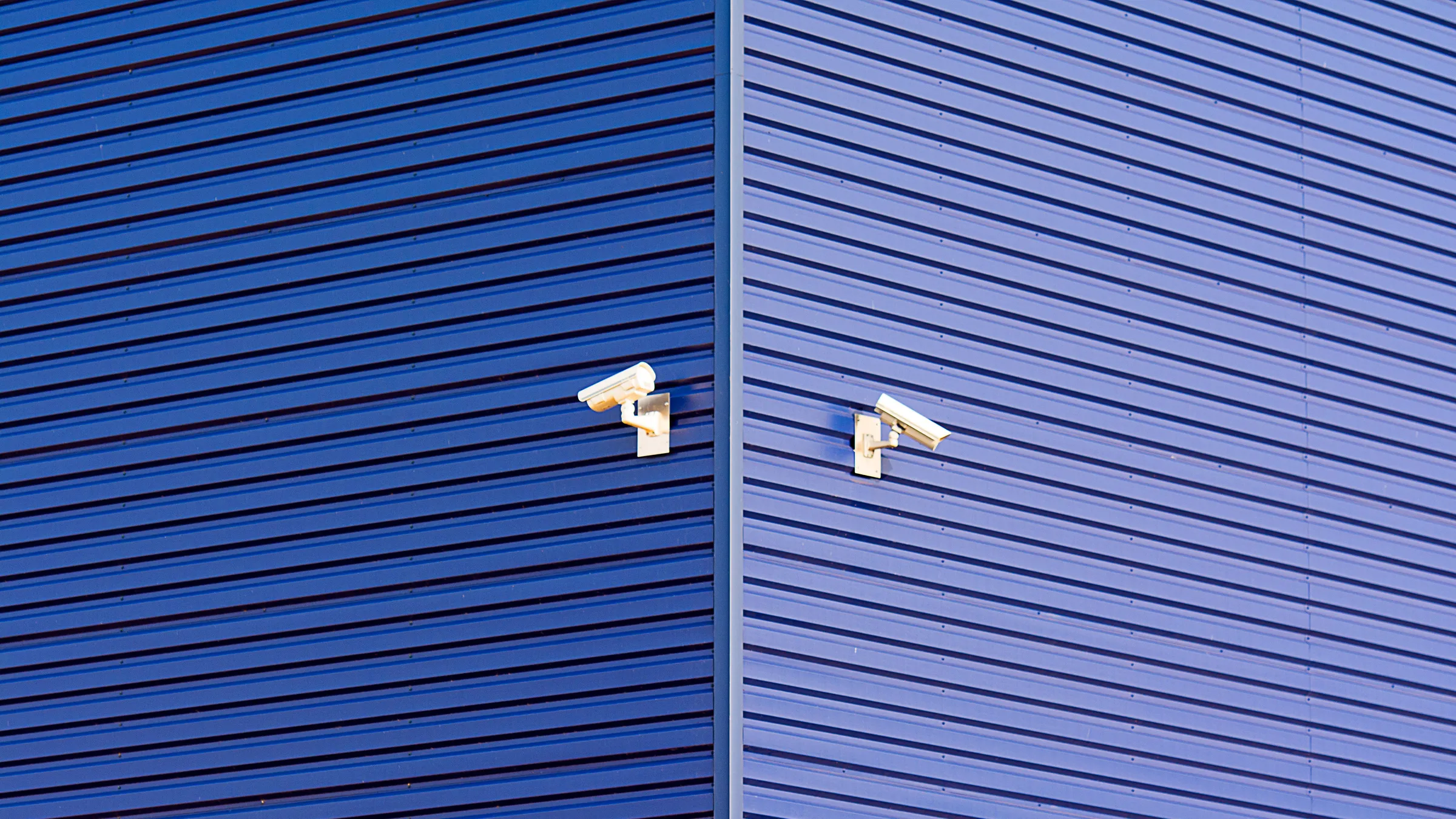 Zwei Überwachungskameras an einer blauen Metallfassade