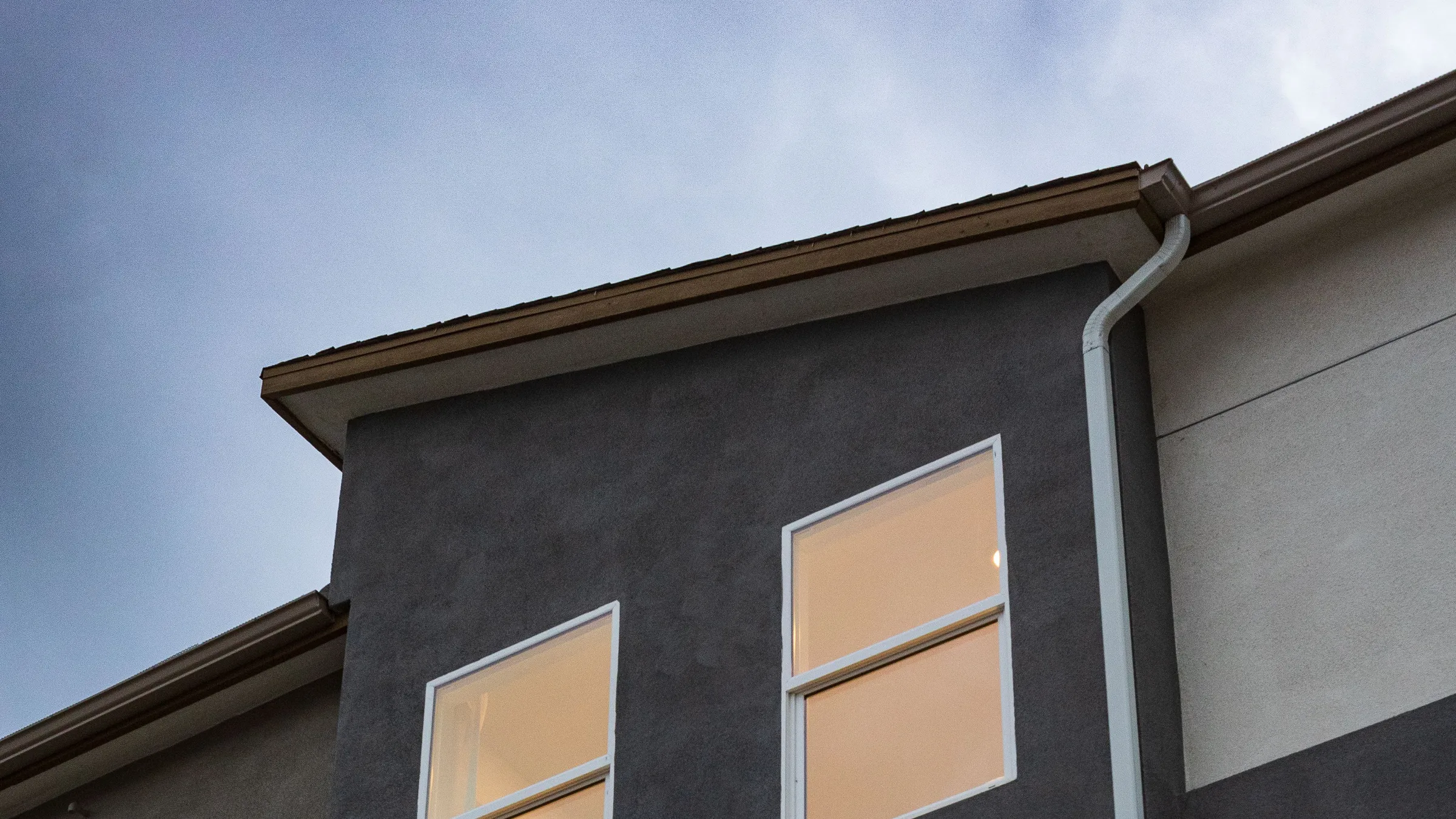 Modernes Wohnhaus in der Abenddämmerung mit warm beleuchteten Fenstern